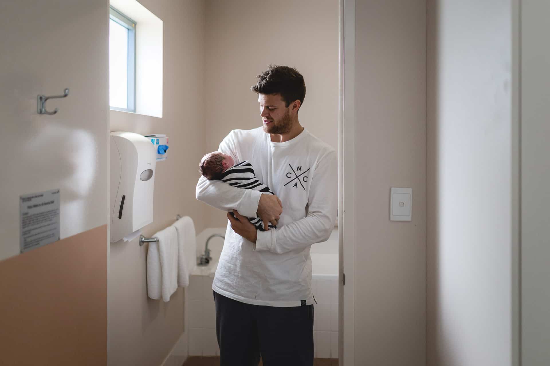 Newcastle Birth Photographer Angela Hardy captures Sonny's dad holding him after birth